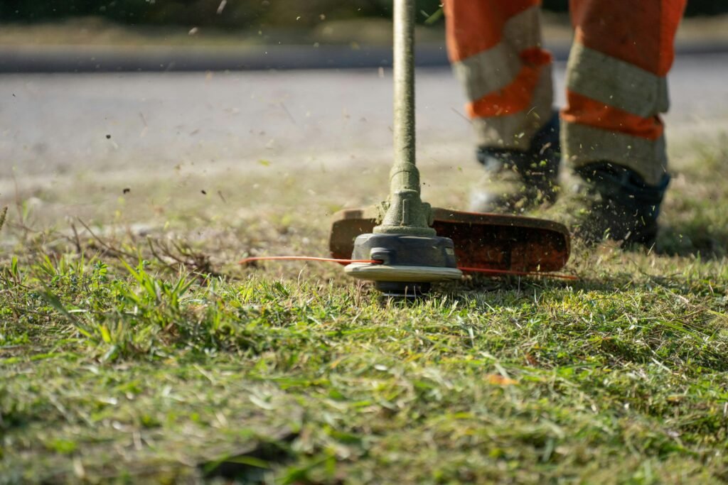 pexels photo 11400235 11400235 Close-up of a person trimming grass with a power tool outdoors.