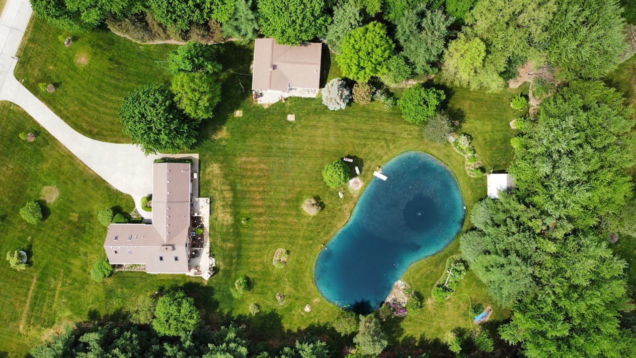 The Art of Drawing Readers In: Your attractive post title goes here Bird's eye view of rural houses and a pond surrounded by lush greenery in Almont, Michigan.